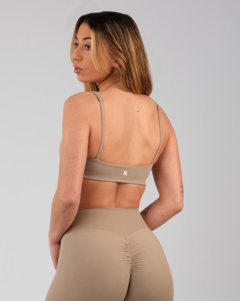 Vue de dos d'une femme en brassière camel, tournant la tête vers l'arrière.
