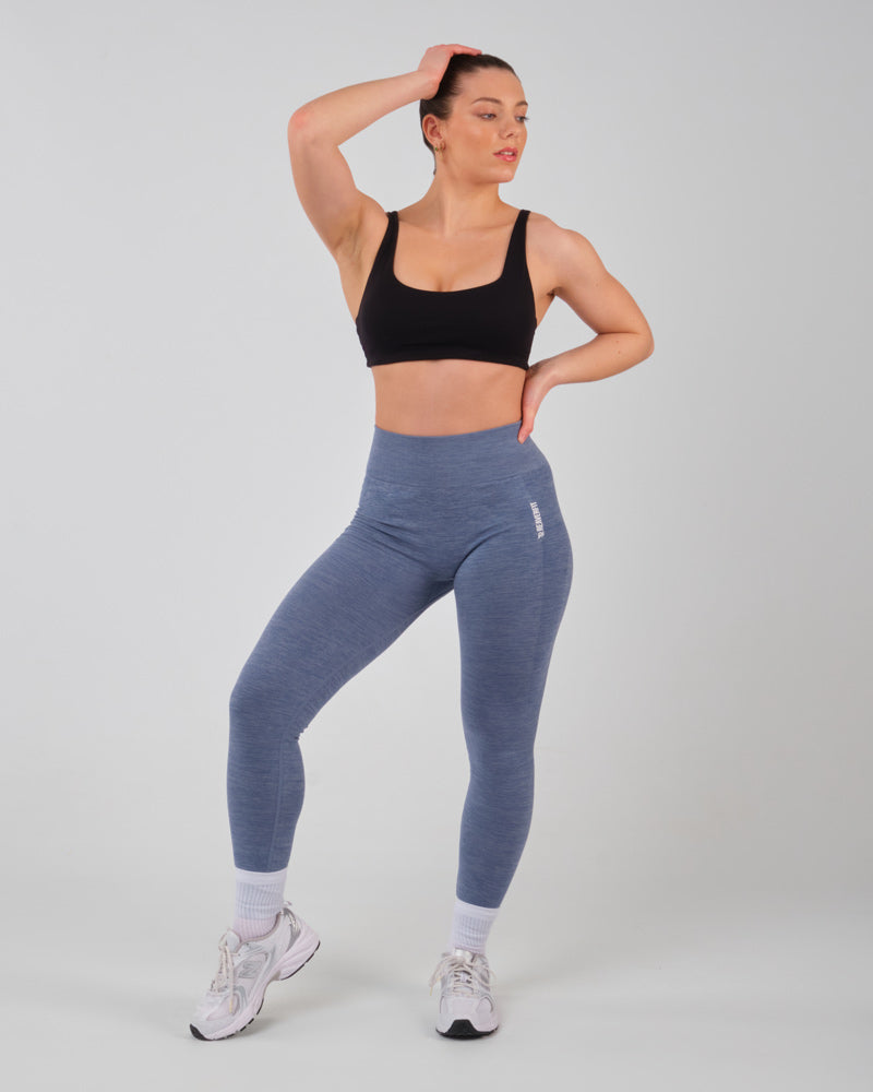 Modèle féminin en tenue de sport avec legging bleu AMBER, vue de face, jambe sur la pointe de pieds.