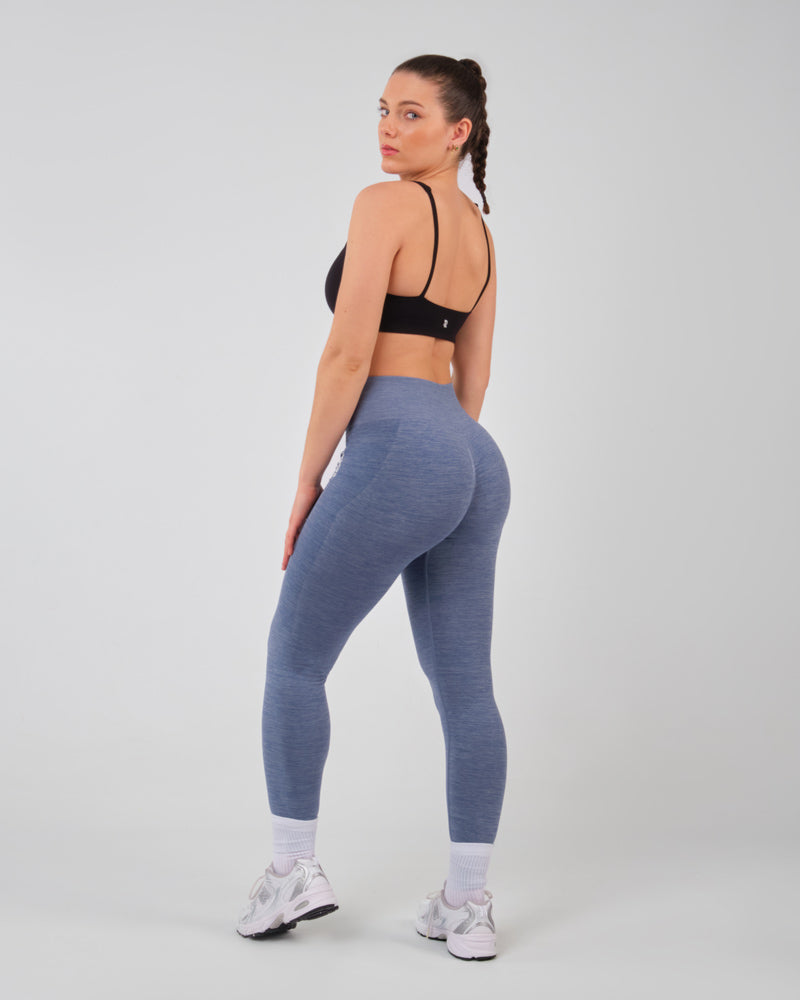Modèle féminin portant le legging bleu AMBER en position de fitness, illustrant l'élasticité et le confort du tissu.