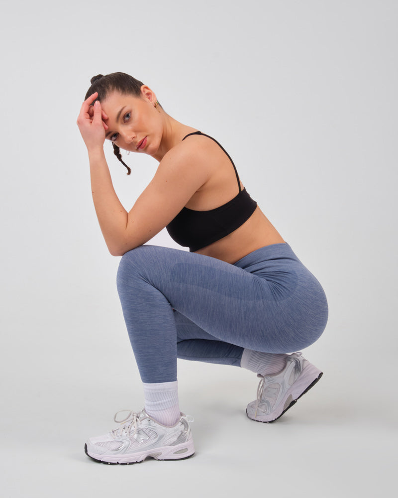 Modèle en position accroupie portant le legging bleu AMBER, mettant en avant la durabilité et l'adaptabilité du tissu à divers mouvements.