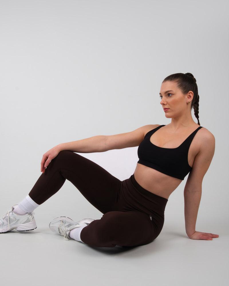 Modèle assis en tenue de sport avec legging AMBER marron, vue de côté.