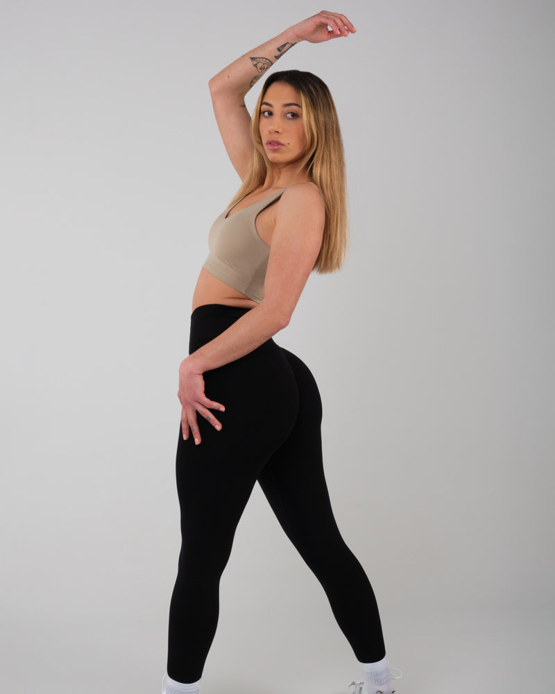 Modèle féminin étirant le bras vers le haut, portant le legging AMBER noir, mettant en avant la flexibilité du tissu