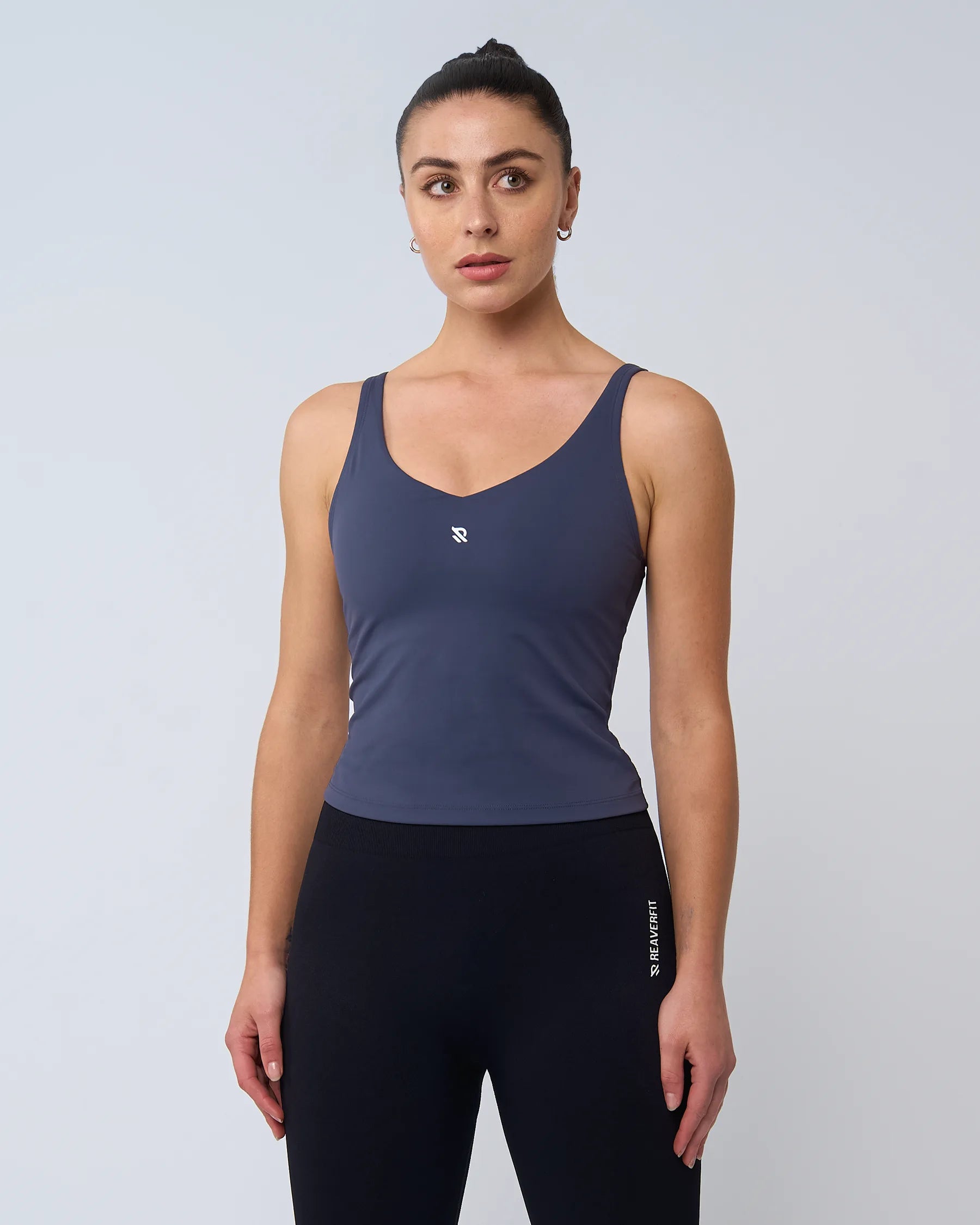 Femme portant le débardeur AURA bleu de Reaverfit, coupe ajustée, parfait pour le fitness, extensible et respirant.