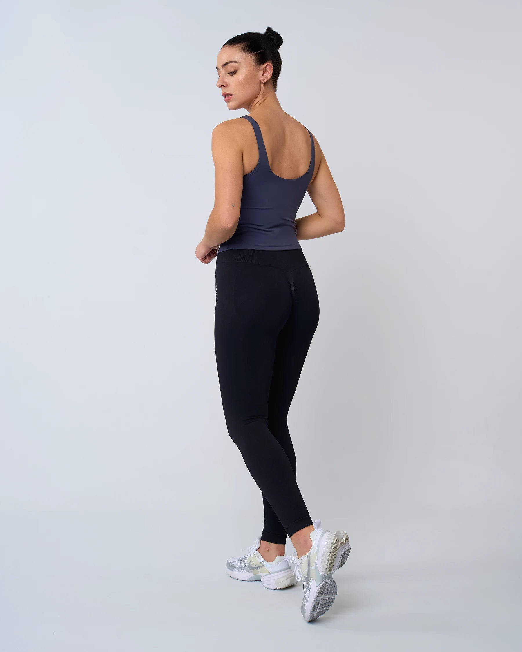Vue de dos d'une femme en débardeur AURA bleu Reaverfit, montrant les bretelles croisées et la coupe ergonomique pour le running.