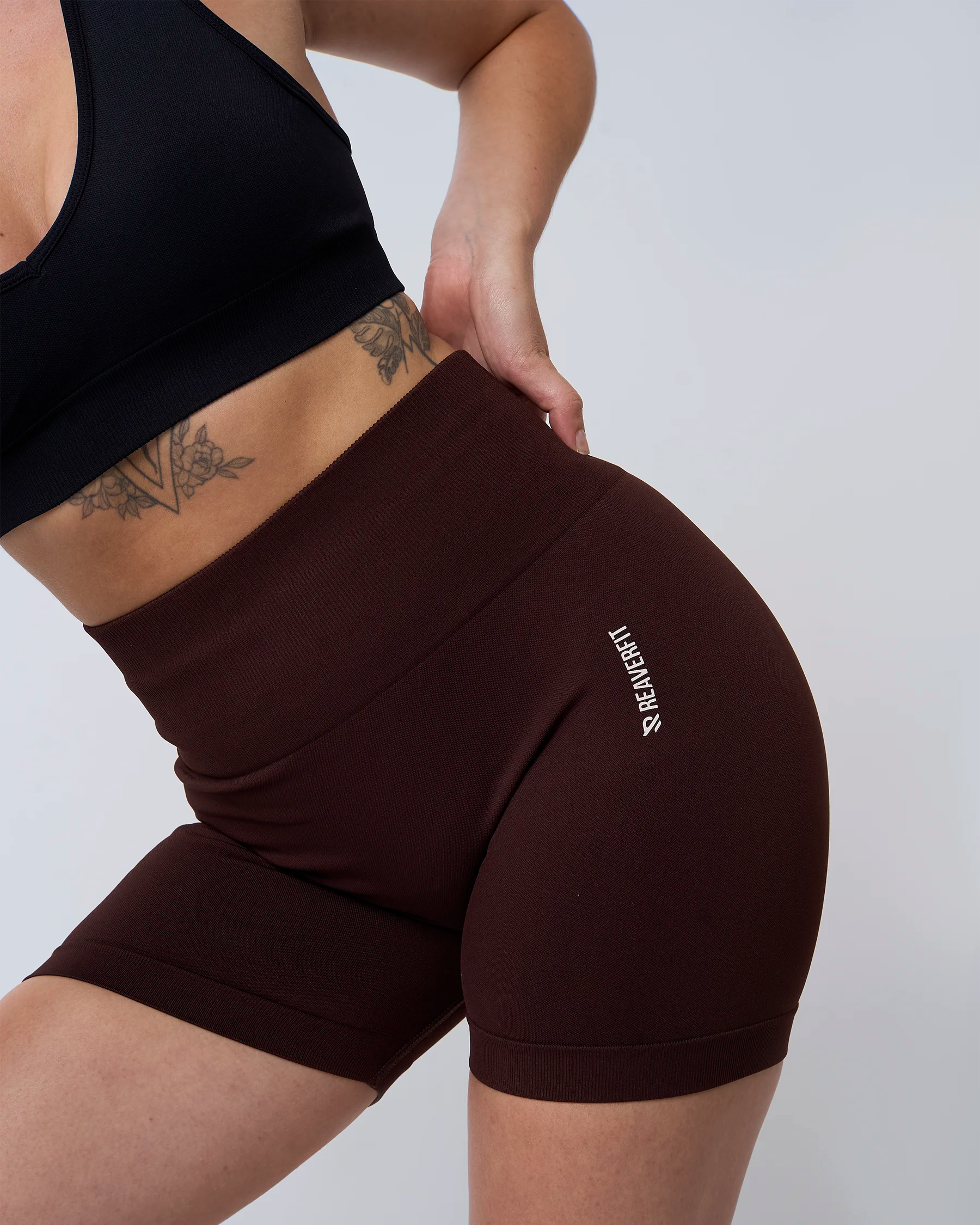 Short Reaverfit en expresso pour femme, zoom sur le logo de la marque, mettant en avant le design élégant et la qualité du tissu, idéal pour les activités sportives.