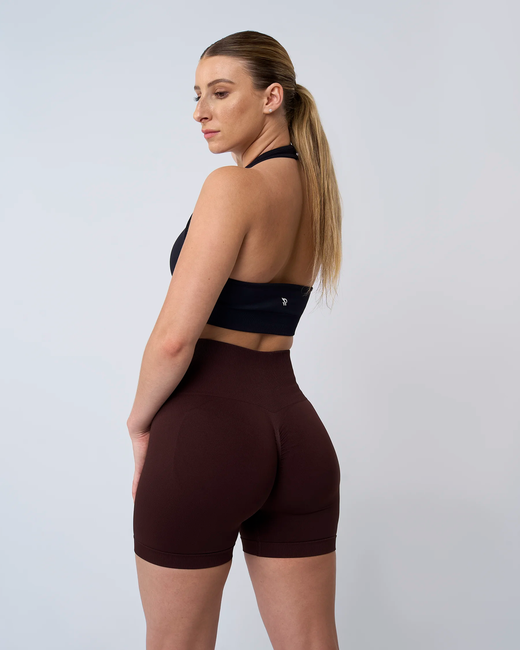 Short de fitness Reaverfit expresso pour femme, vue de profil, mettant en valeur la silhouette grâce à sa coupe sculptante et son tissu résistant et opaque.