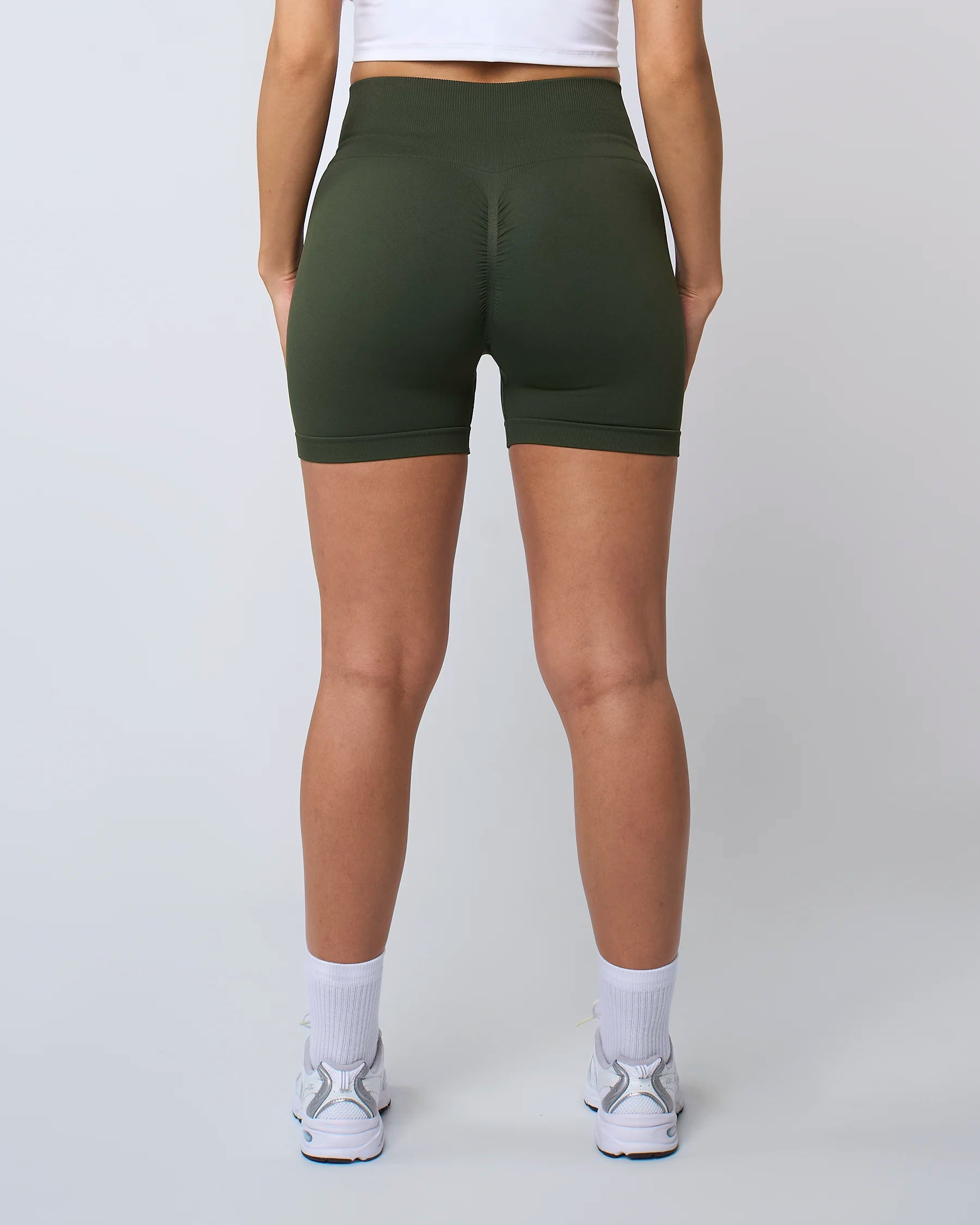 Short de sport taille haute Reaverfit Sculpt en kaki pour femme, vue arrière, avec une couture scrunch pour un effet push-up et un tissu extensible pour un confort optimal.