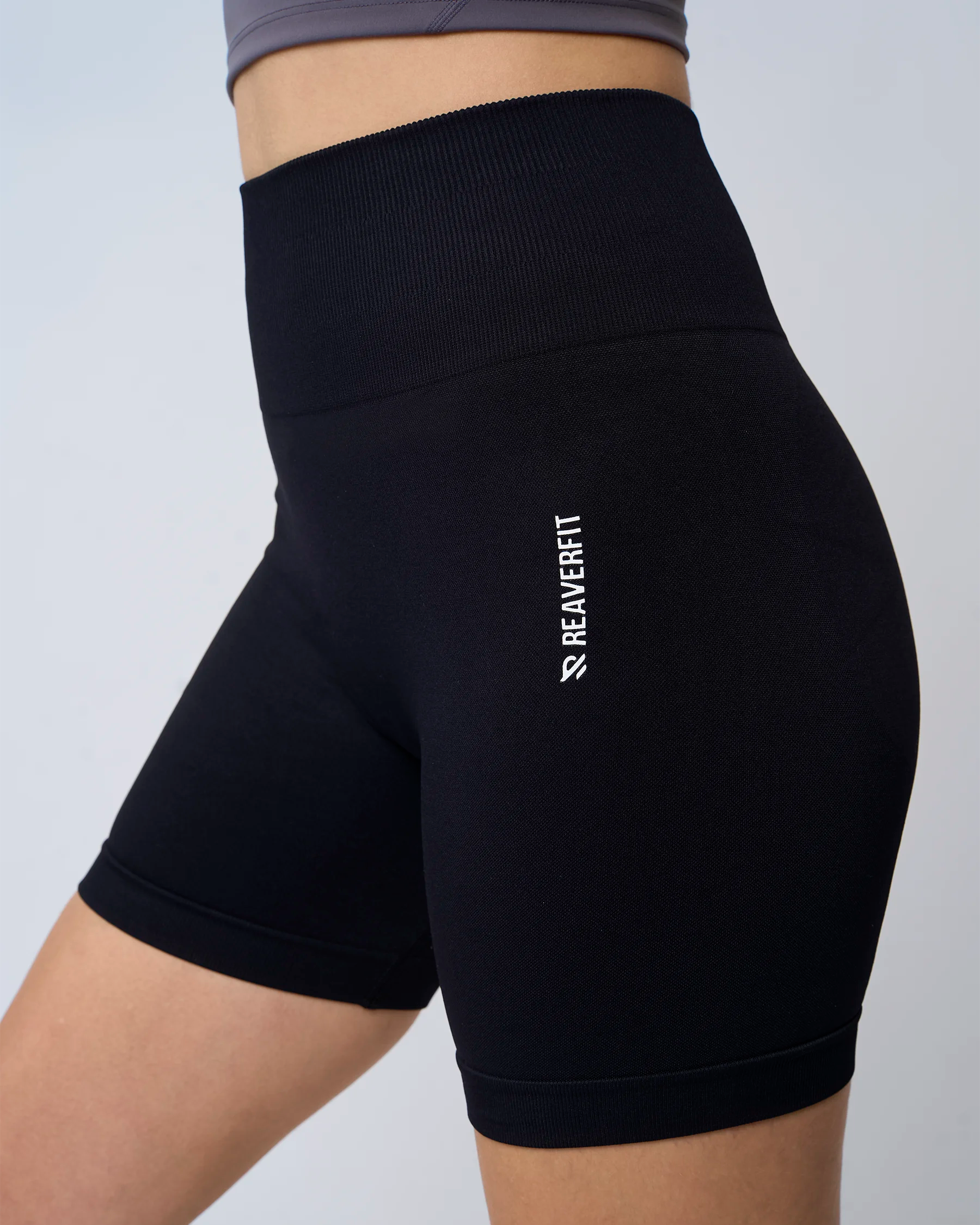 Vue latérale short Reaverfit noir femme, taille haute, effet push-up, extensible et résistant pour le fitness.
