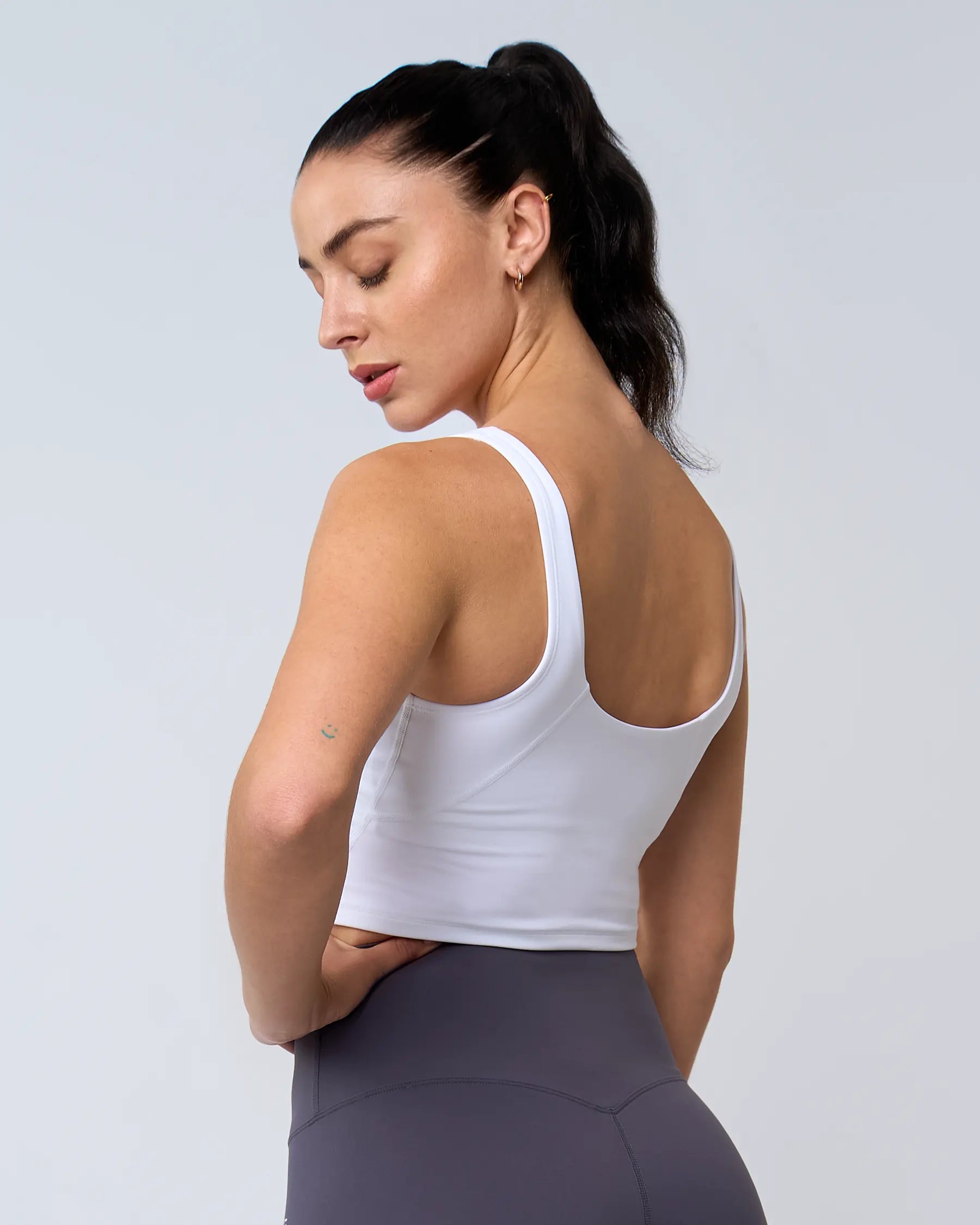 Modèle portant un débardeur à brassière intégrée blanc pour le sport et pour les femmes.