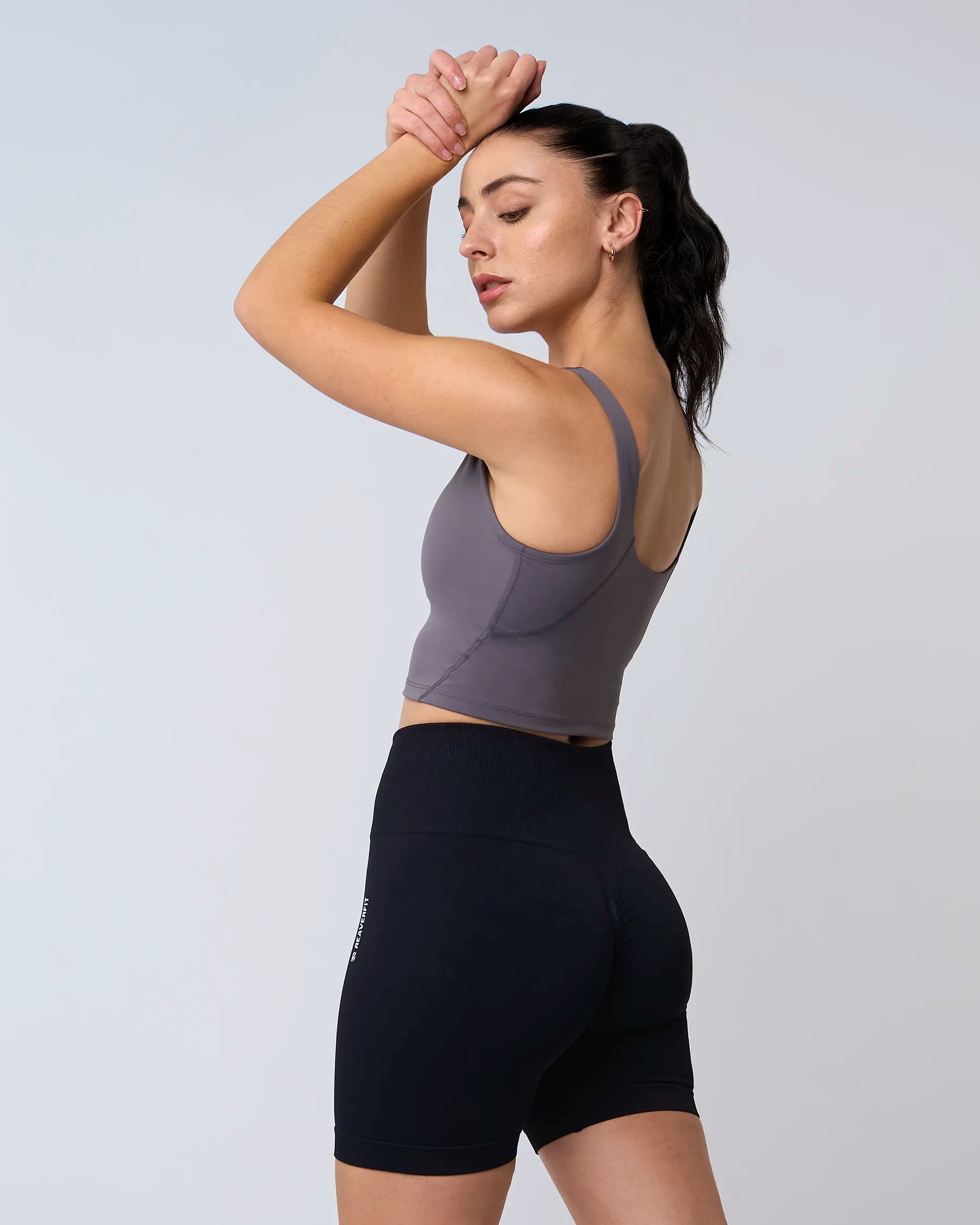 Modèle portant la brassière sport PURE gris, vue de profil avec le bras sur la tête