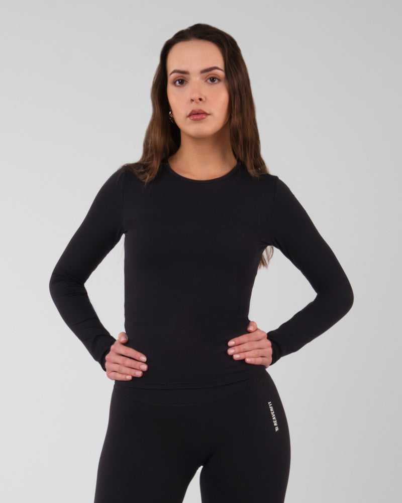 Vue de trois quarts d'une femme en haut à manches longues ALMA noir durable et haute performance pour le sport en salle.