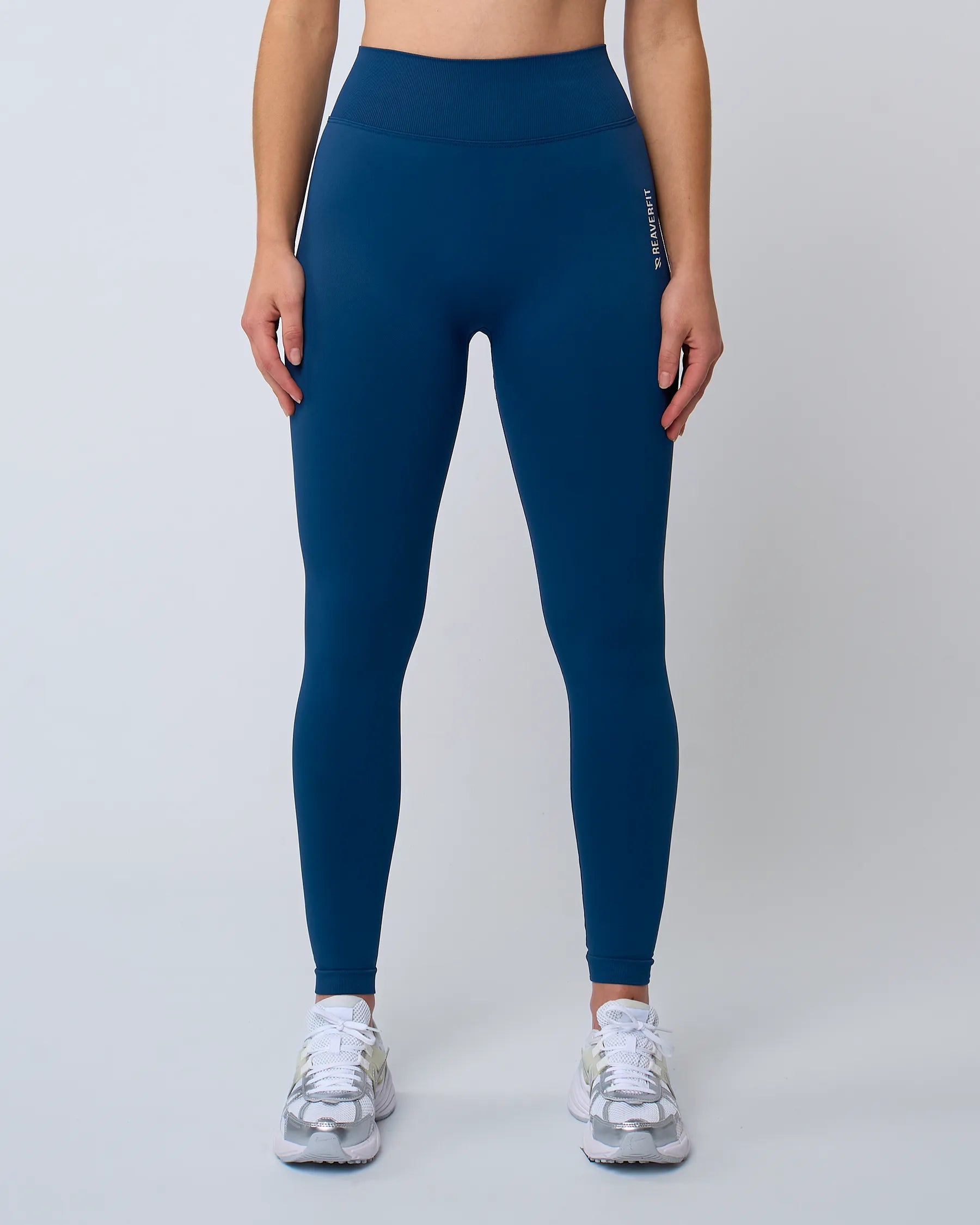 Femme debout en legging AZUR bleu Reaverfit, vue de face, conçu pour les mouvements fluides et les séances de fitness.
