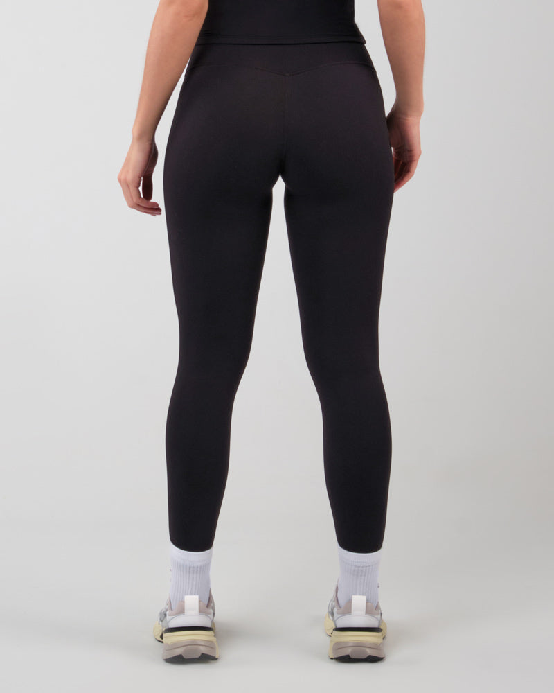 Vue arrière d'une femme en legging ALMA noir, soulignant la coupe ajustée et le soutien pour une activité physique en salle de sport et le confort pour être confortable au quotidien.