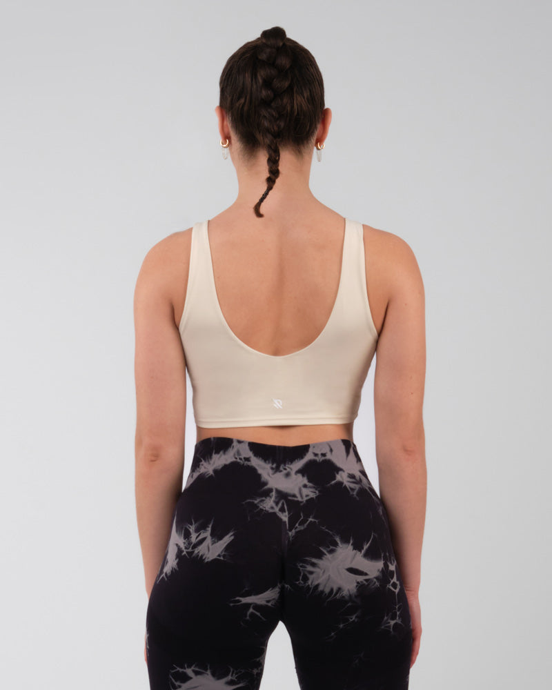 Vue arrière d'une brassière de sport crème montrant le soutien dorsal, conçue pour le fitness et les activités de haute intensité