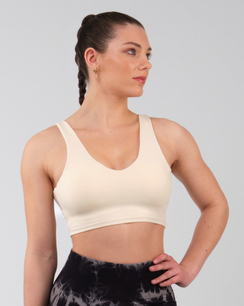 Brassière de sport beige coupe classique vue de côté, mise en avant du design élégant et du confort pour l'entraînement.