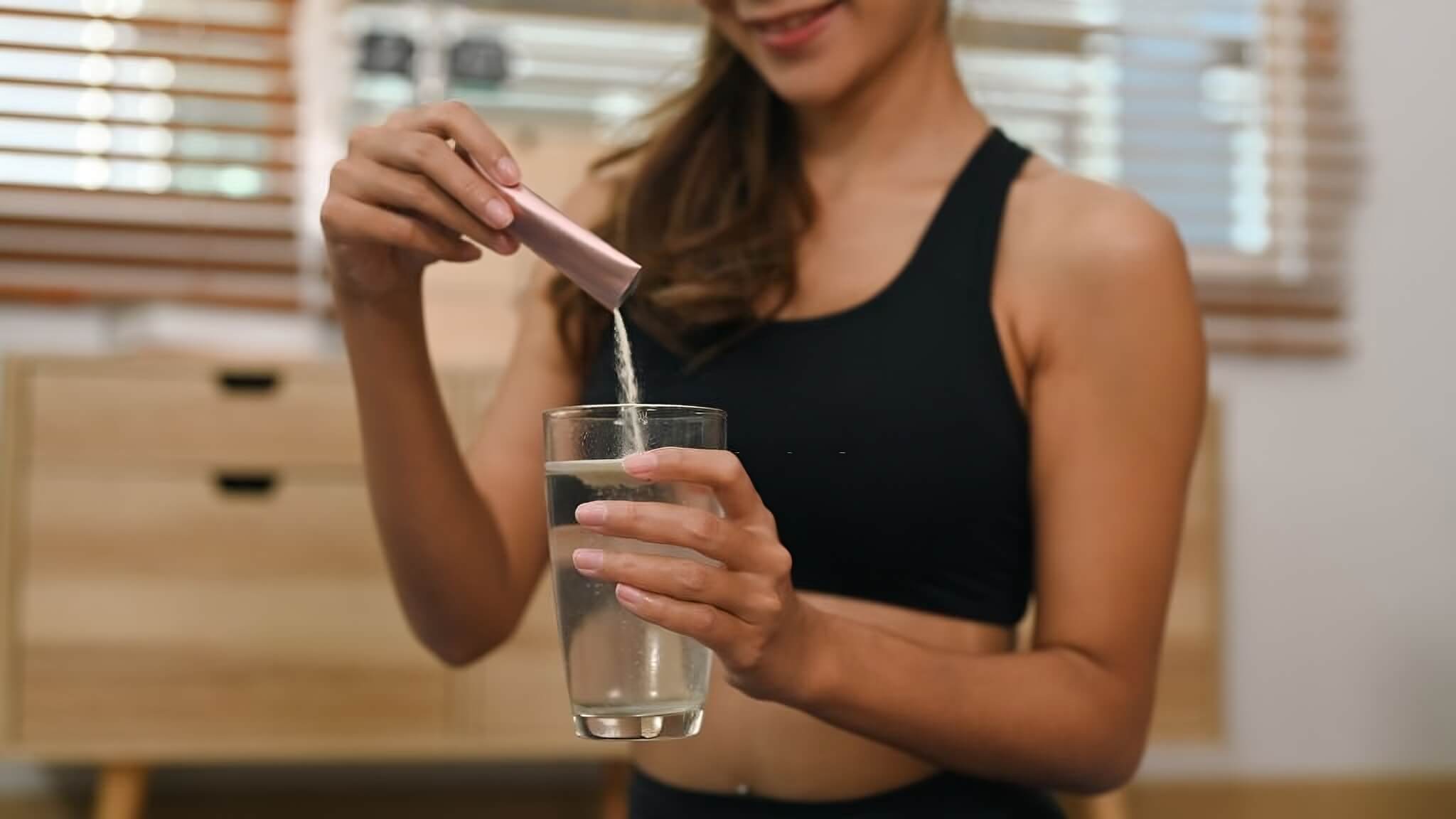 femme dissolvant de la poudre de collagene marin dans un verre d'eau supplément sain pour la récupération musculaire