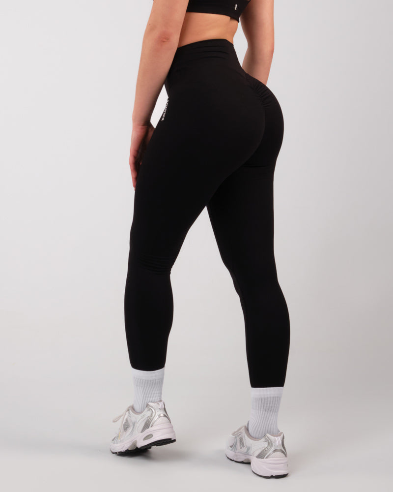 Vue de profil droit d'une femme portant des leggings noirs sportifs, prête à courir.