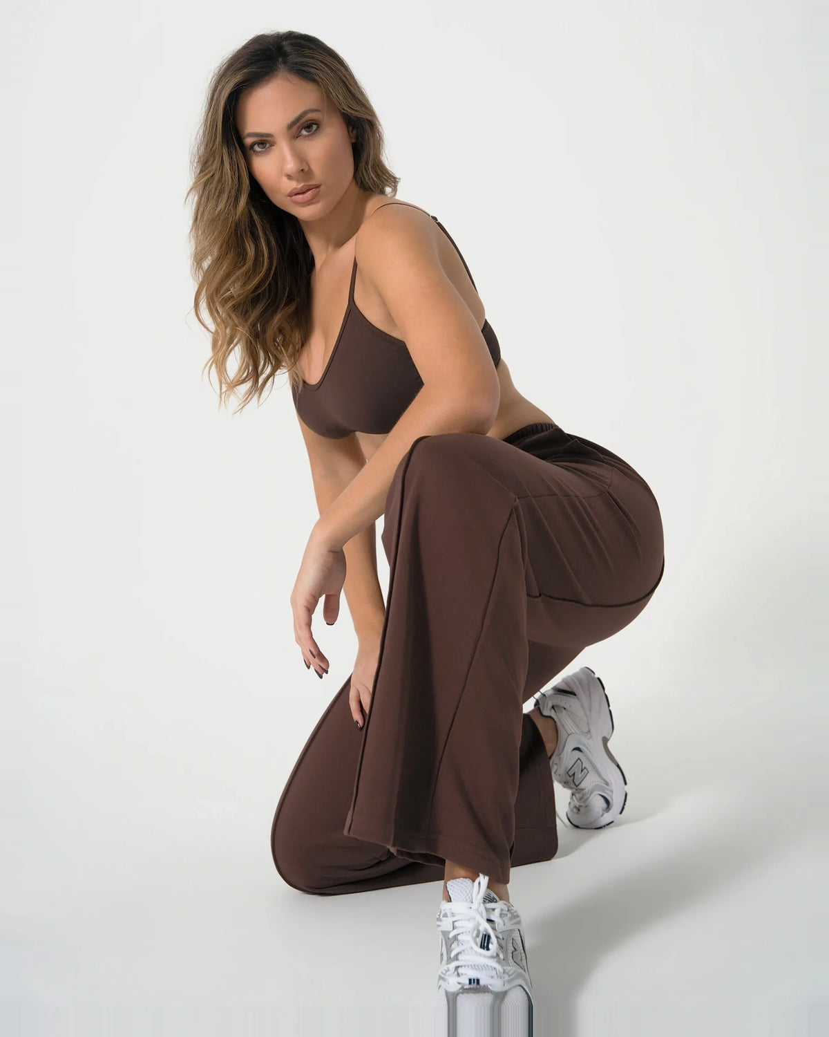 Jogging ICÔNE marron Reaverfit pour femme, porté en position accroupie.