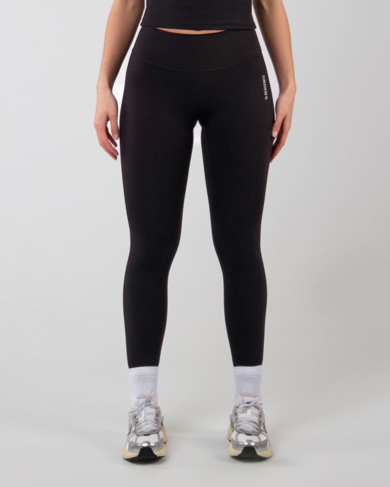 Vue de côté d'une femme en legging ALMA noir, démontrant la flexibilité et la coupe ergonomique pour le sport et l'exercice.