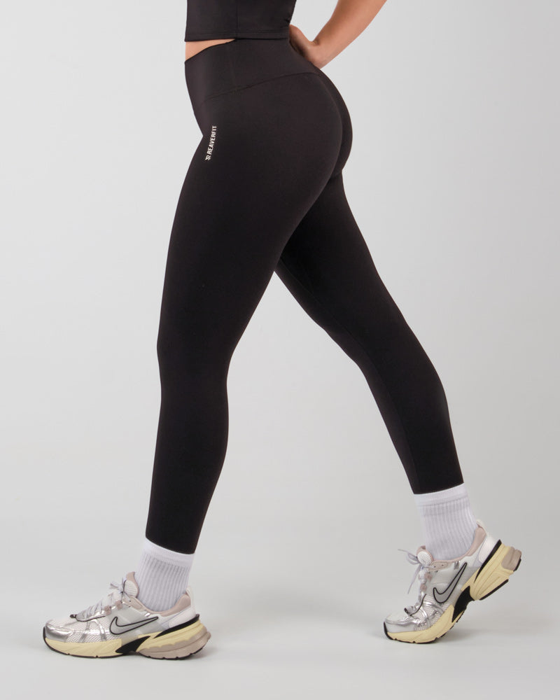 Vue de profil d'une femme en mouvement, portant des leggings de sport ALMA noirs, conçus pour épouser les formes et favoriser la performance.