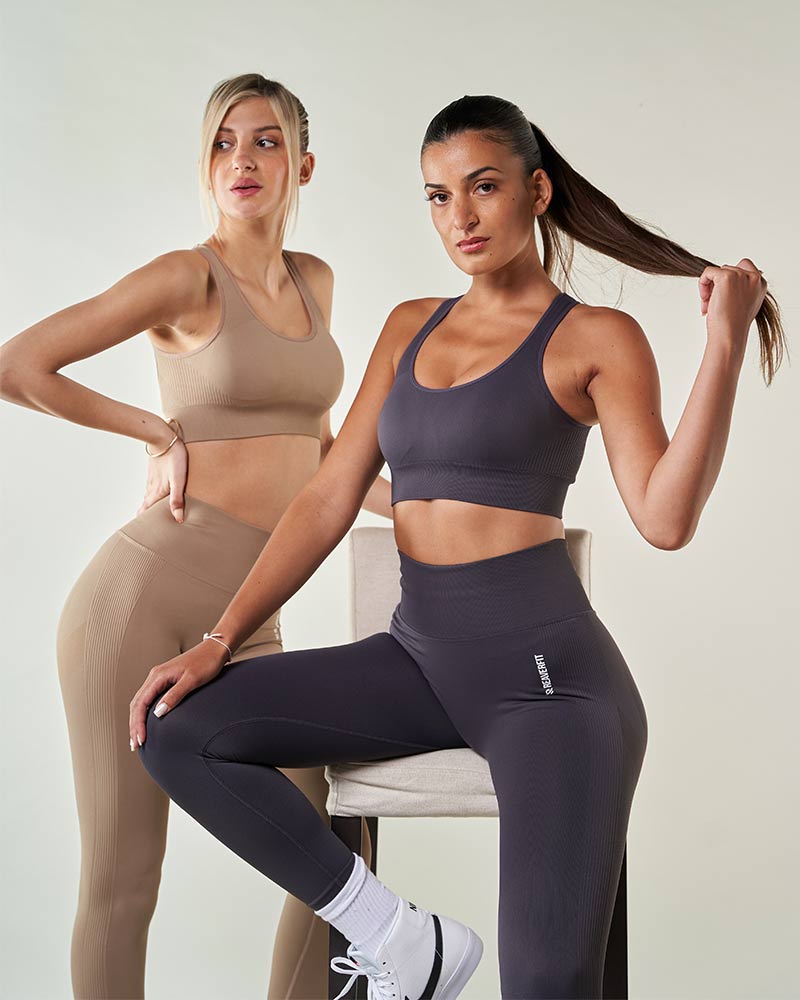 2 jeunes femmes portants de beaux ensembles de sport bleu et beige tendance Brassière de sport confortable et réglable, conçue pour un soutien optimal pendant l'entraînement