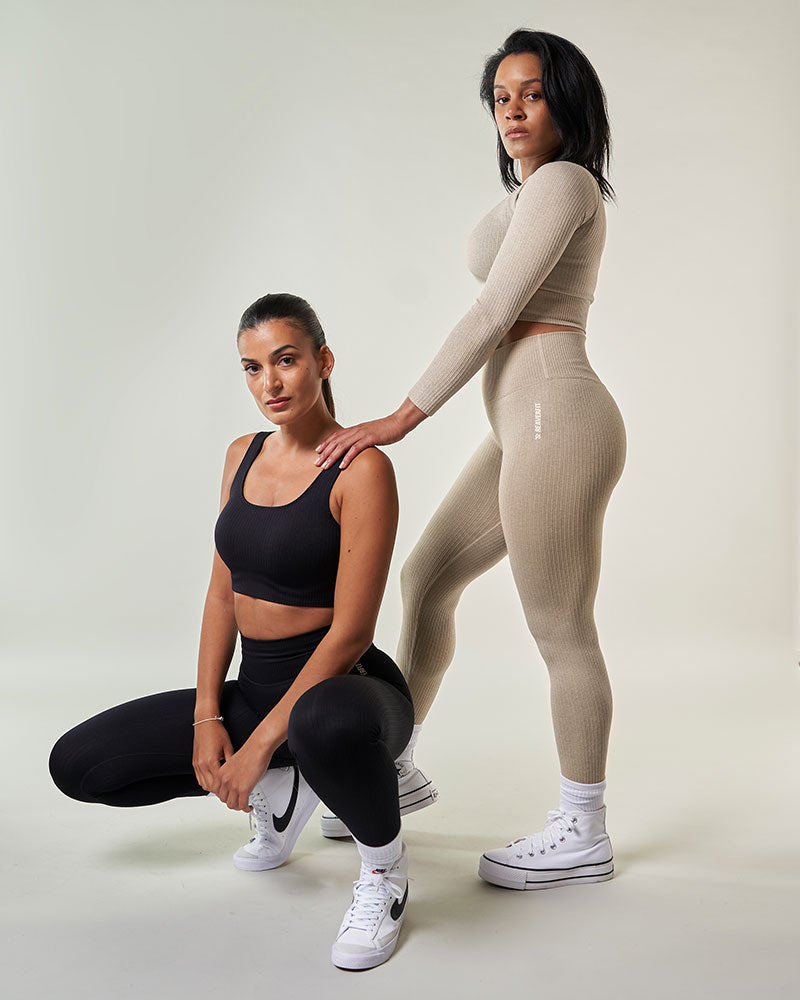 deux jeunes femmes portant des tenues de sport chic et athleisure crop top et legging taille haute noir et beige exemple de look sportif chic
