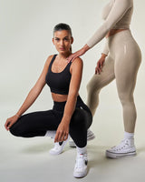 2 jeunes femmes portants de beaux ensembles de sport noir et beige sportswear Brassière de sport confortable et réglable, conçue pour un soutien optimal pendant l'entraînement