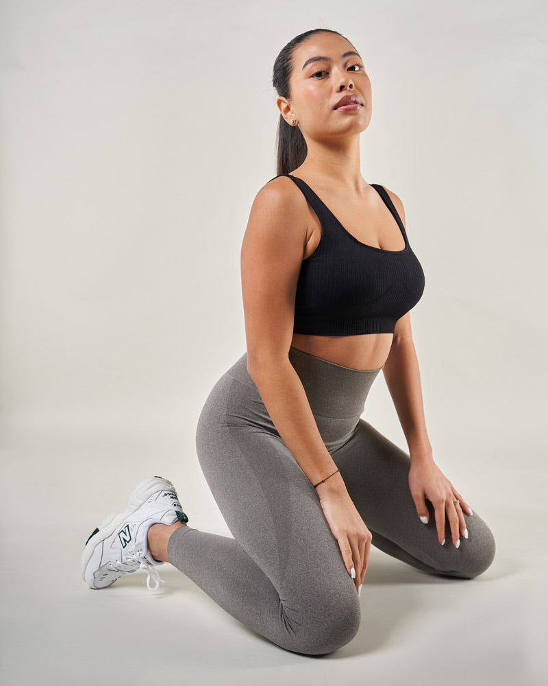 Femme qui porte le Legging de sport taille haute Gris foncé et crop top sport noir - Conçu pour le sport liberté de mouvement inégalée